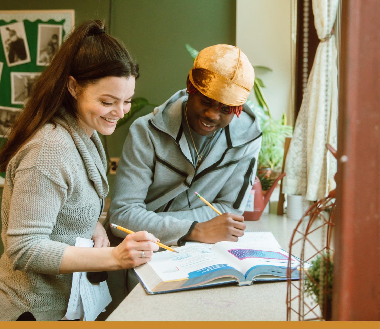 two people looking at a book with pencils in hand